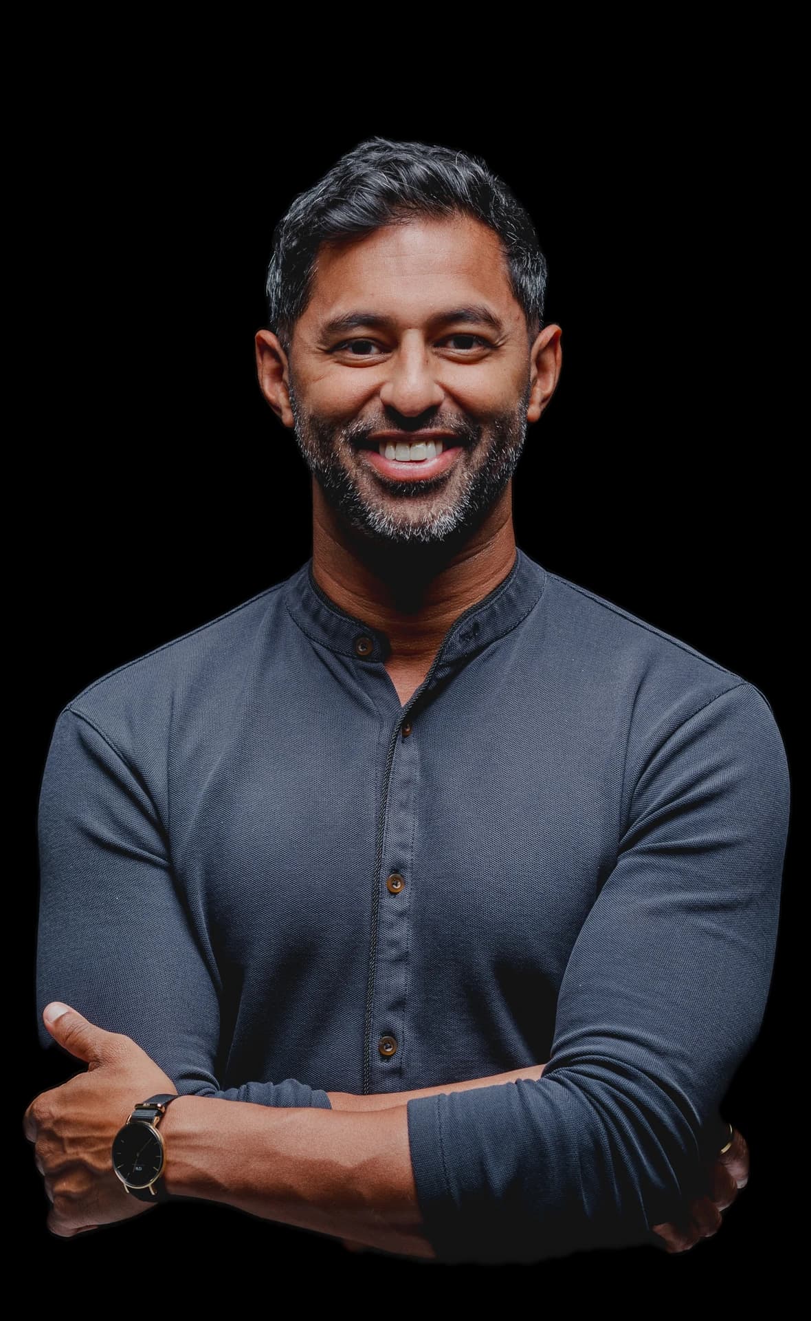 Ben Comstock, arms crossed, in a slate collarless shirt, smiling.